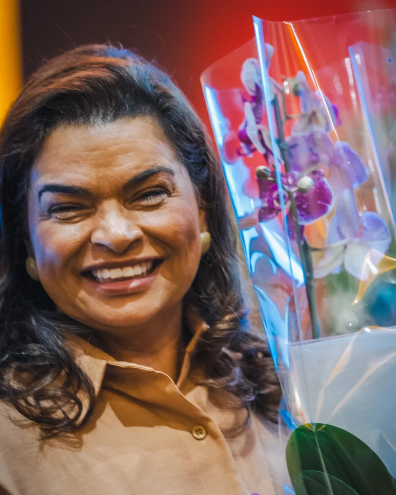Marizete Rodrigues sorrindo com uma orquídea